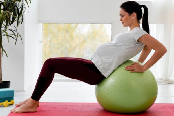 Mulher gravida fazendo exercícios de fisioterapia com a bola. Representação de fisioterapia na gestação.